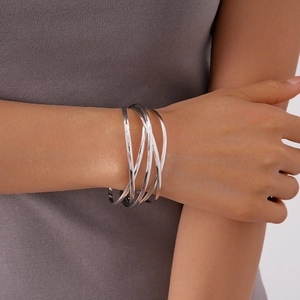 Close-up of a silver multi-layered geometric open cuff bracelet on a model's wrist