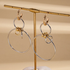 Detail view of gold and silver mixed metal geometric earrings on a jewelry stand