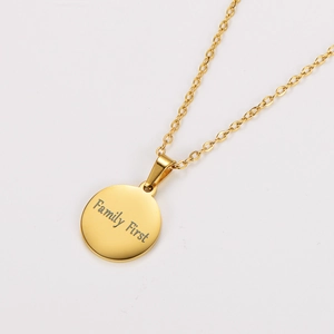 Close-up of golden necklace with Family First engraved round pendant on white background