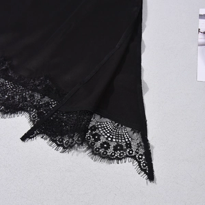 Close-up of black satin camisole featuring delicate eyelash lace trim and side slit hem