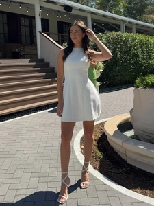 Detail of white sleeveless A-line dress featuring high neck and cinched waist for summer