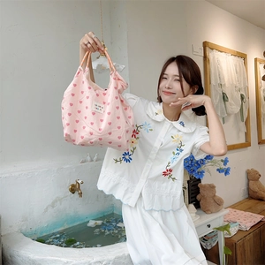 Pink heart pattern tote bag carried by model in white floral embroidered shirt