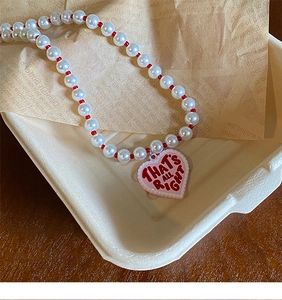 Close-up of pearl necklace with pink heart pendant in a vintage gift box