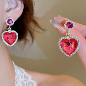 Gros plan de boucles d'oreilles cœur avec pierres précieuses roses et détails dorés