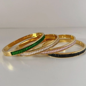 Vue détaillée de quatre bracelets dorés sertis de zircons de couleur taille émeraude