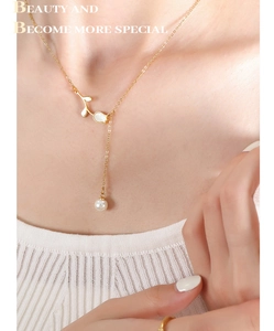 Close-up of a 18K gold plated rose flower necklace with a white pearl on a woman's neck