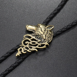Macro shot of bronze wolf head pendant and black braided leather bolo tie necklace