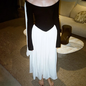 Detail of elegant off-shoulder black knit top and high-waisted white maxi skirt dress