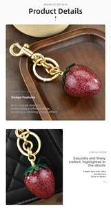 Macro detail of red glitter strawberry keychain with gold hardware on a handbag
