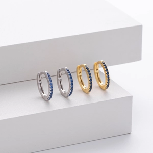 Detail of gold and silver S925 sterling silver huggie earrings with inlaid blue gemstones