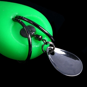 Macro detail of fishing lure with green body, silver spinner blade, and swivel hook parts