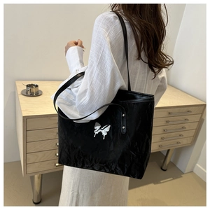 Detail of a black tote bag featuring a metallic liquid butterfly and glossy finish
