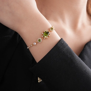 Détail du bracelet plaqué or avec pierre ovale verte et strass scintillants sur le poignet