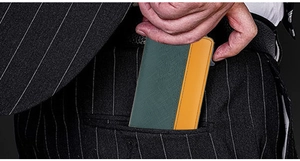 Slim RFID blocking card holder for men being placed in a stylish suit trousers pocket
