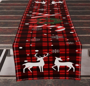 Detail view of rustic linen Christmas table runner with red plaid and reindeer patterns