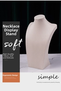 Macro detail of beige velvet bust display stand for necklaces on white marble surface
