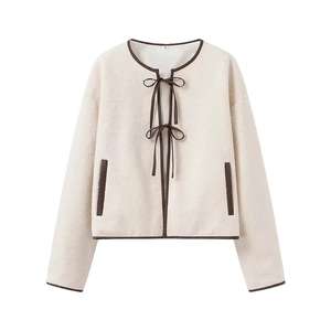Veste en fausse fourrure blanc crème avec bordure marron et fermeture à nœud papillon