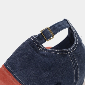 Detail of adjustable metal buckle and contrast stitching on navy canvas baseball cap