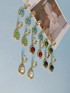 Detailed set of golden hoop earrings with colorful turquoise, ruby, and pearl pendants
