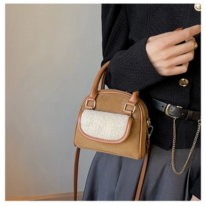 Detail of plush brown suede handbag with white faux fur trim and gold metal hardware