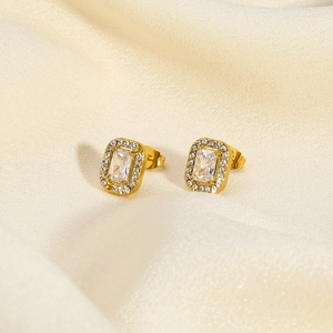Detail of gold emerald-cut earrings with cubic zirconia on soft beige silk background
