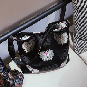 Detail of floral butterfly embroidery on black satin jacquard fabric for tote bag