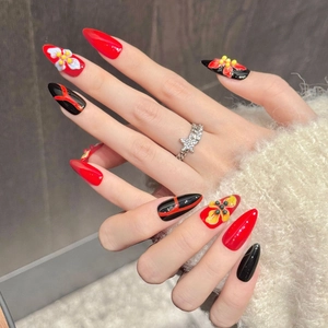 Détail de faux ongles amande avec fleurs 3D rouges et lignes noires peintes à la main