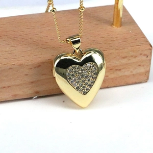 Macro shot of gold heart locket necklace with pavé zircon inner heart on bead chain