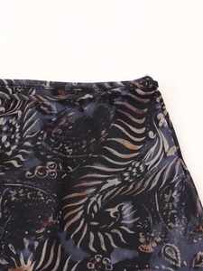 Gros plan détaillé sur un tissu en maille foncé avec des motifs paisley dorés et bleus