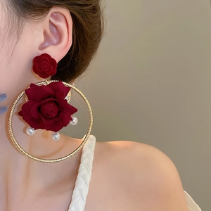 Detail of elegant velvet red rose earrings with golden hoops and white hanging pearls