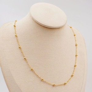 Elegant gold titanium steel beaded ball chain necklace displayed on a jewelry bust stand