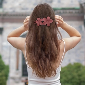 Detailed back view of a matte dusty rose flower hair claw clip on long wavy hair
