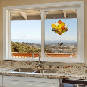 Close-up of honeycomb suncatcher with realistic bee pendant hanging in front of a window