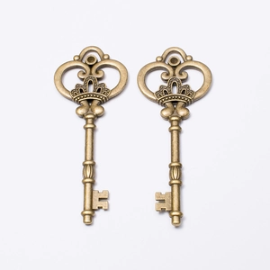 Pair of vintage crown key pendants in antique bronze alloy finish on white background
