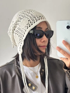 Détail du bonnet au crochet blanc avec motifs floraux ajourés et longs liens