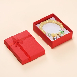 Beaded bracelet with green leaf and crystal charms in a red bow gift box packaging