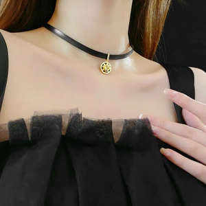 Close-up of a gold starburst medallion pendant on a black choker necklace worn by a model