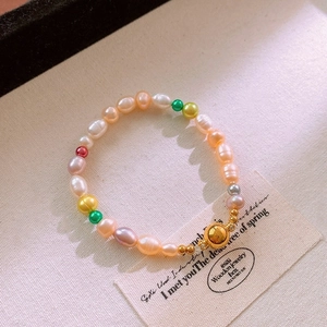 Gros plan de perles multicolores et fermoir doré sur un fond minimaliste chaleureux
