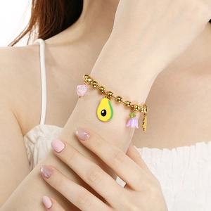 Golden bead bracelet with colorful avocado and floral charms on model wrist