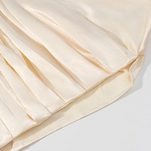 Detail von elegantem cremefarbenem Satinstoff mit vertikaler Plissee-Struktur und Glanz