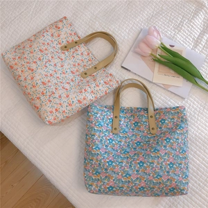 Detail of floral tote bags with leather handles and metal rivets in a lifestyle setting