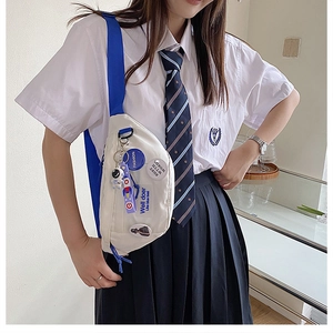 Detail view of canvas crossbody bag with astronaut pendant and decorative badges