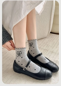 Detail of light grey polka dot socks with bow print and wavy edge trim in Mary Janes