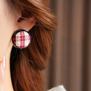 Close-up of minimalist red and white plaid fabric round stud earrings with black trim