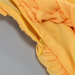 Gros plan détaillé du tissu plissé jaune avec une fermeture éclair invisible discrète