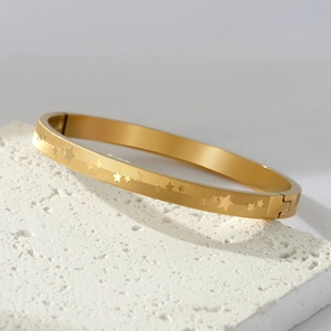 Bracciale rigido in acciaio al titanio dorato con stelle incise e chiusura a fibbia