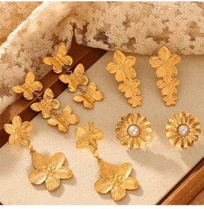 Détail de boucles d'oreilles rétro dorées avec fleurs et papillons sur présentoir beige