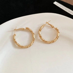 Detailed macro view of twisted gold geometric hoop earrings with matte brushed finish