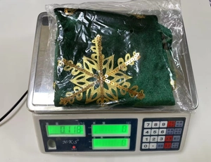 Detail view of a green velvet Christmas stocking with gold snowflakes on a digital scale