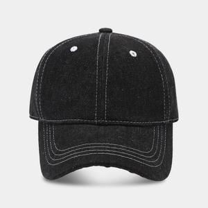Close-up of black denim baseball cap with white contrast stitching and soft crown detail